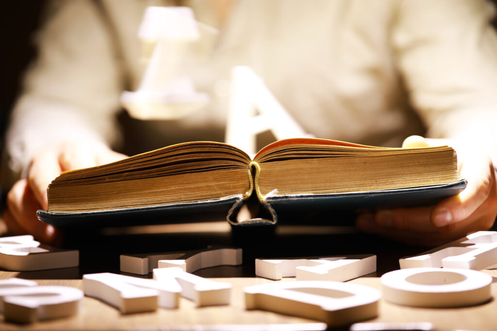 Woman holding an open book with two hands. Light coming out of the book as a concept of learning, education, knowledge and religion