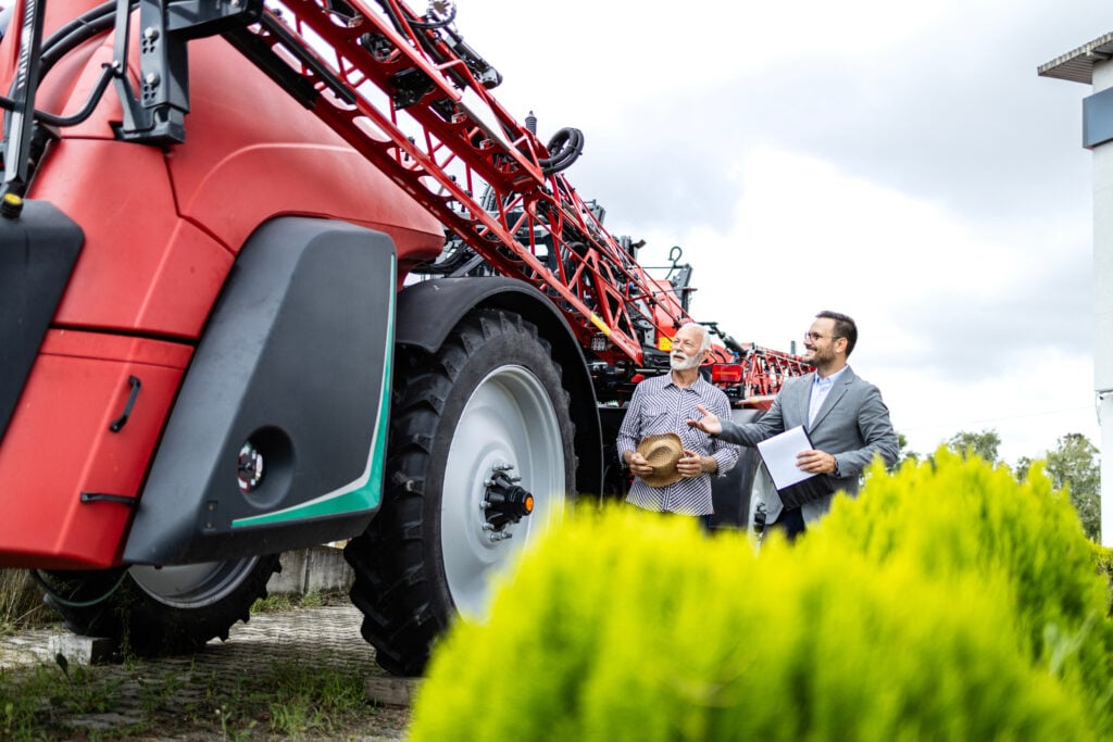 Dealership salesman selling modern agricultural machines to the customer.