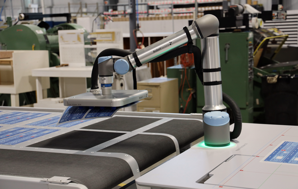 Robotic arm operating on automated label production line at Impact Label manufacturing facility