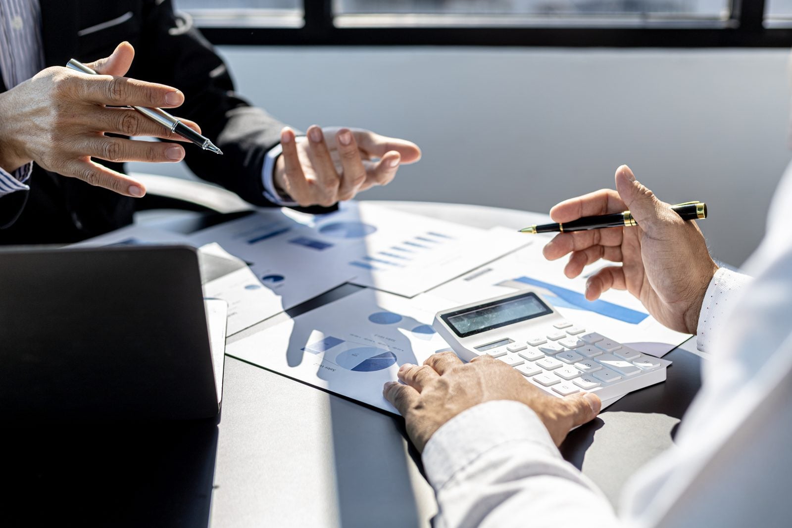 Business professionals reviewing financial charts with a calculator to plan equipment financing