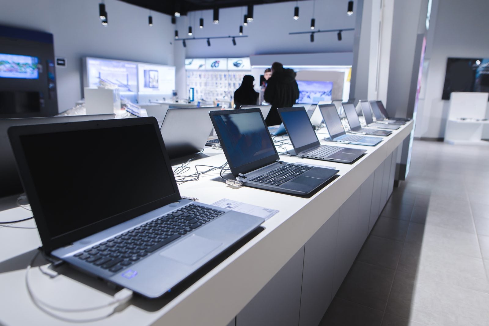 Row of new laptops displayed on a counter in a technology retail store