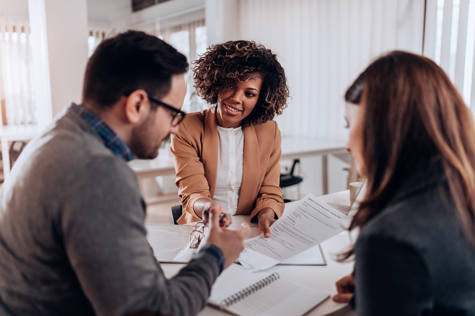 Equipment financing representative reviewing a lease agreement with two business owners at a table